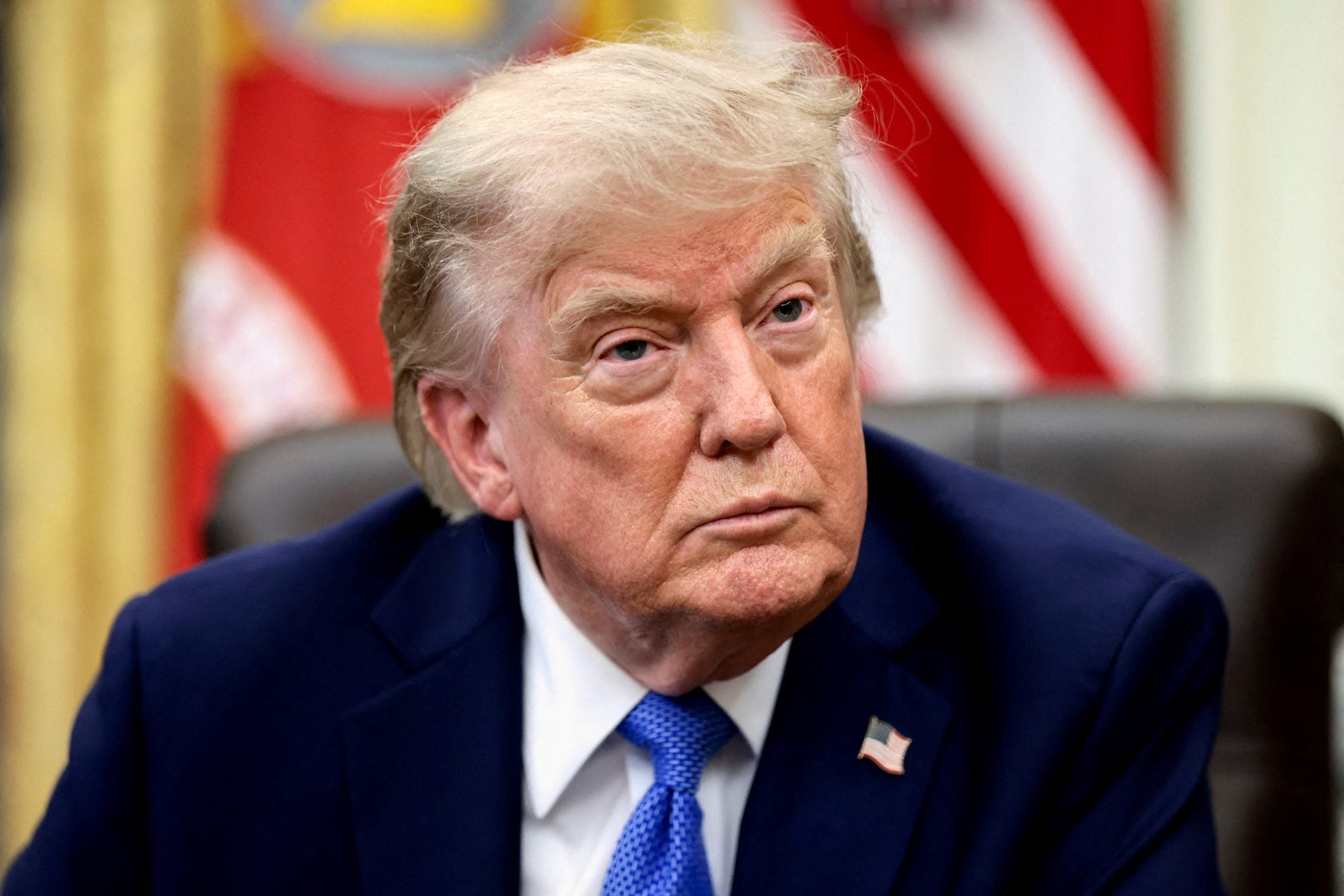 U.S. President Trump looks on as he signs executive orders from the Oval Office of the White House
