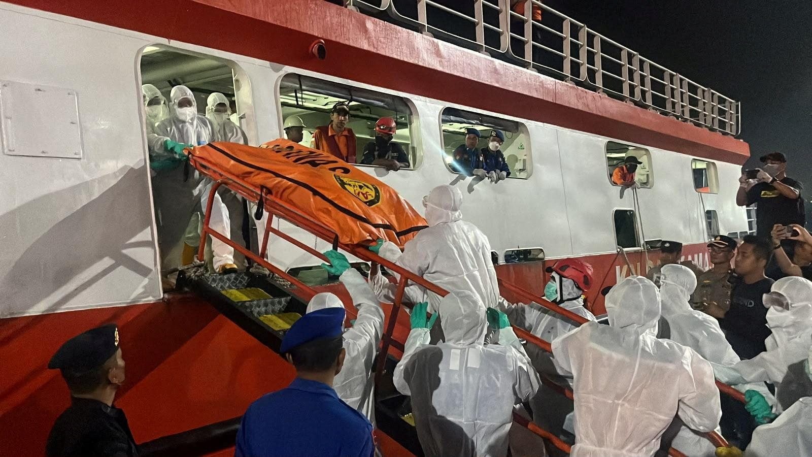 Rescue members wearing personal protective equipment carry a body bag as they retrieve victims of the Virgo Transport 8 ferry