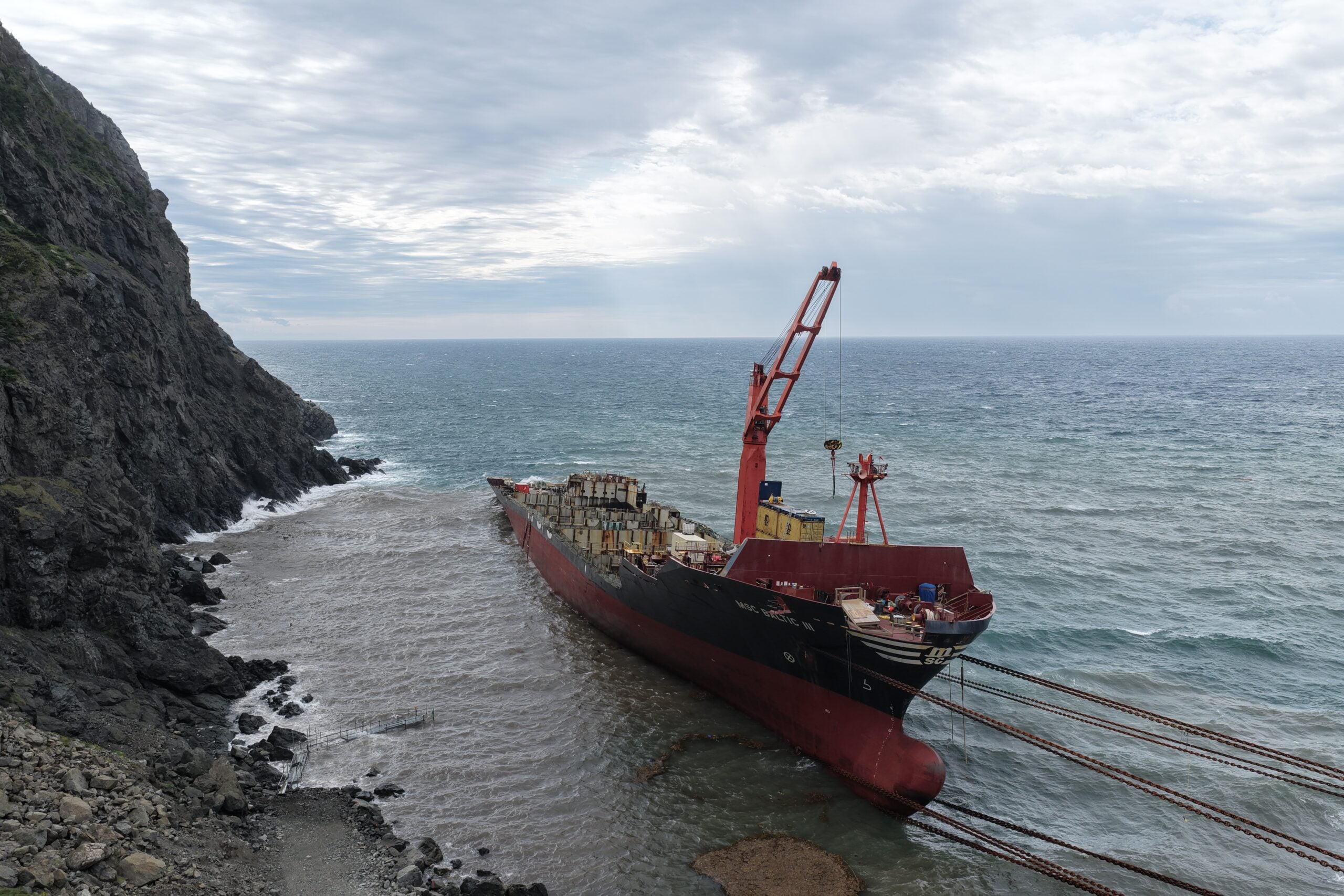 Grounded containership MSC Baltic III being pulled toward shore near Wild Cove, Newfoundland and Labrador, during ongoing wreck removal operations.