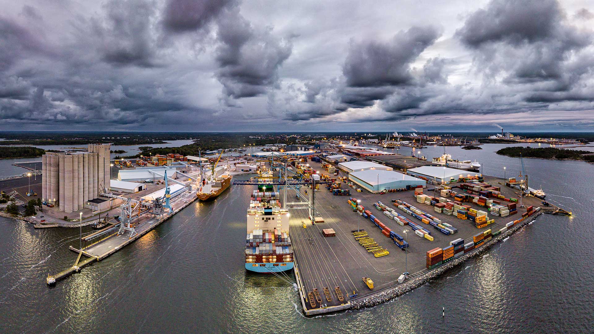 Aerial view of the Port of Rauma in Finland, showing cargo terminals, warehouses, cranes, containers and ships alongside under cloudy skies.