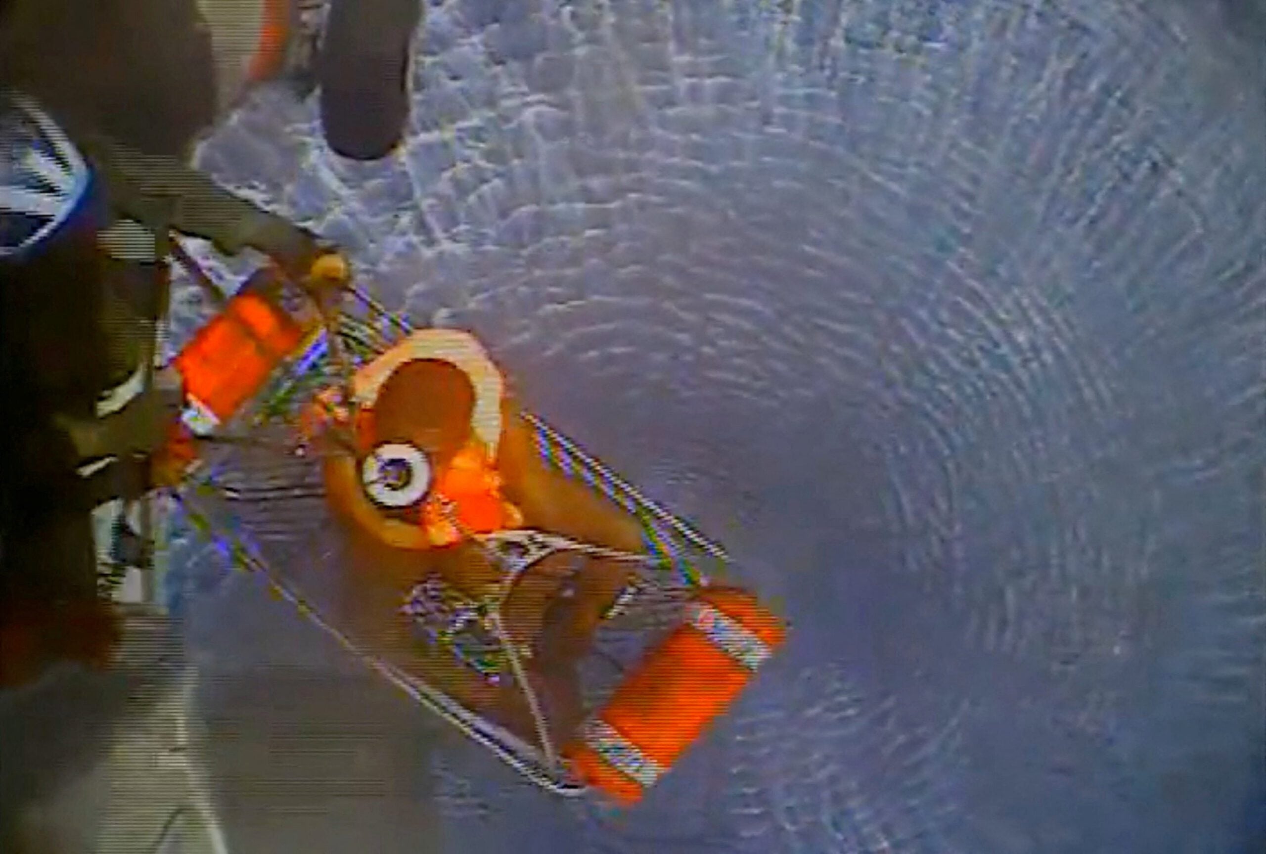 An aerial view shows a person rescued from the water being pulled into a helicopter after a vessel capsized off the coast of Mona Island