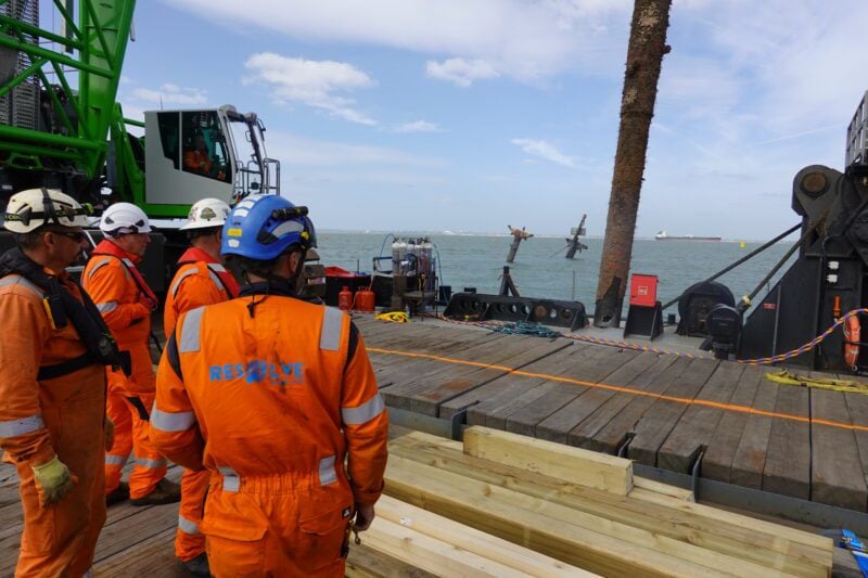 Resolve Marine workers stand on a crane barge beside the exposed masts of the SS Richard Montgomery wreck in the Thames Estuary.