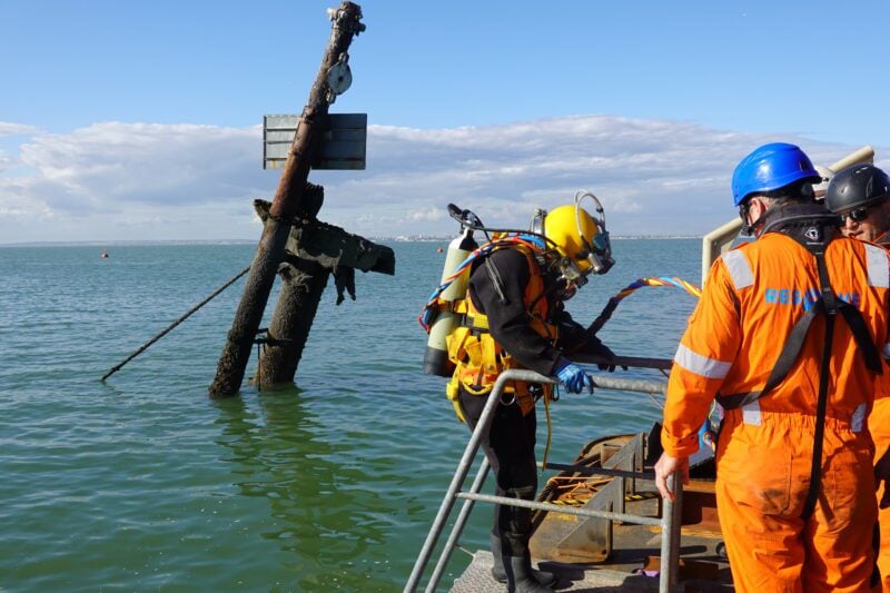 Resolve Marine diver prepares to enter the water beside the exposed remains of the SS Richard Montgomery wreck in the Thames Estuary.