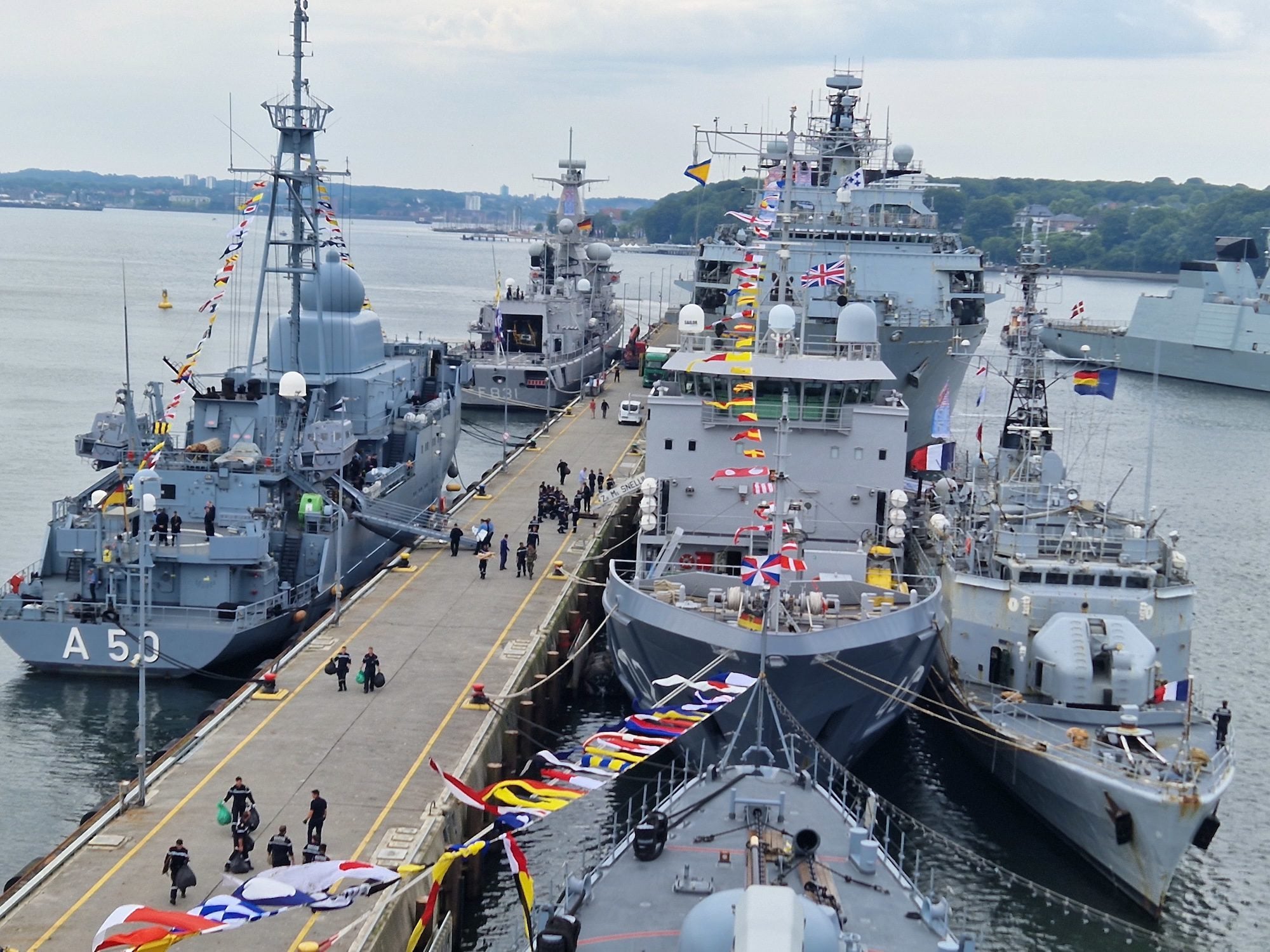 NATO warships moored alongside a pier in Kiel, Germany, during a multinational naval exercise.